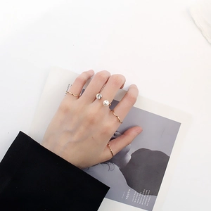 Ensemble de bagues dorées avec anneaux ondulés, perle et zircon portés à la main