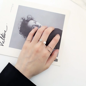 Détail de bagues en argent avec perles et diamants portées sur un magazine de mode