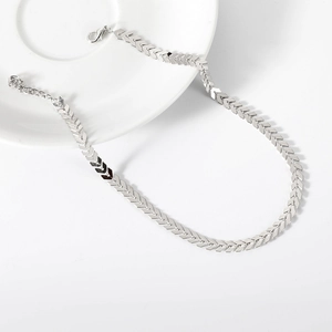 Detail view of silver herringbone choker necklace with V-shaped links on a white plate