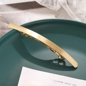 Barrette à cheveux minimaliste en métal doré au design incurvé sur une assiette décorative