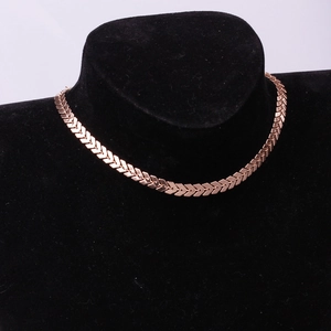 Detailed close-up of rose gold fishbone chain necklace on a black velvet neck mannequin