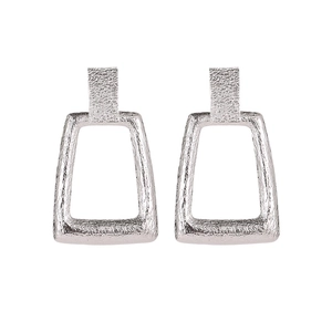 Vue détaillée de boucles d'oreilles géométriques argentées avec une texture métal martelé