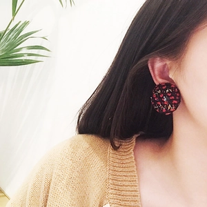 Close-up of vintage red plaid tweed button earrings worn by a model in soft lighting