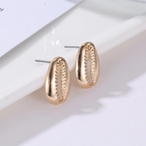 Macro view of gold shell stud earrings with polished mirror finish and silver pins
