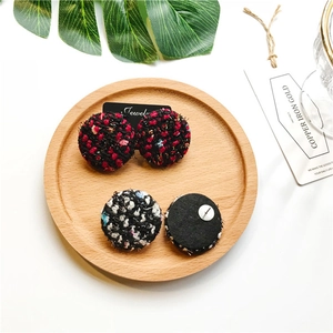 Vintage checkered tweed round earrings in red and blue displayed on a wooden tray