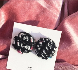 Close-up of vintage black and white tweed fabric round earrings on white card display