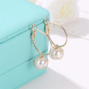 Elegant gold hoop earrings with spiral wrapped pearl charms on a jewelry box