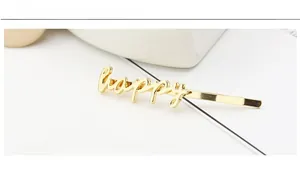 Detailed view of polished gold alloy hair clip featuring happy lettering design