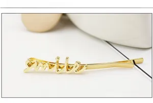 Detailed close-up of golden smile letter hair clip with polished alloy finish on white