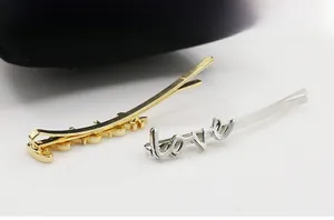 Detailed view of polished gold and silver metal love letter hair clips on a display
