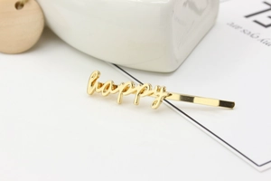 Detailed close-up of a minimalist golden alloy hair pin with a stylish happy letter design