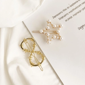 Dettaglio di fermagli per capelli dorati con perle a stella e design con strass