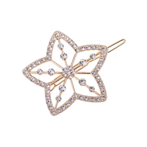 Barrette étoile évidée dorée avec cristaux et perles sur fond blanc pur