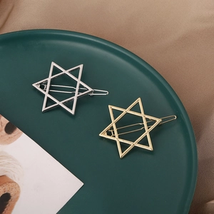 Stylish gold and silver star-shaped metal hair clips set on a decorative plate