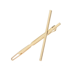Détail de deux barrettes dorées minimalistes en alliage de formes linéaire et ondulée