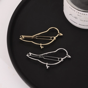 Set aus minimalistischen gold- und silberfarbenen Haarklammern in Vogelform auf Tablett