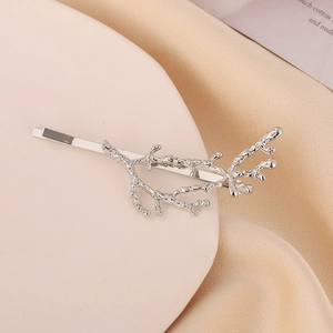Barrette à cheveux branche argentée avec texture corail sur fond crème minimaliste