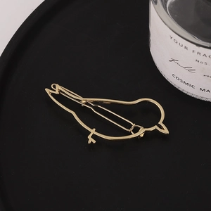 Minimalistische goldene Haarklammer in Vogelform auf einem edlen schwarzen Teller