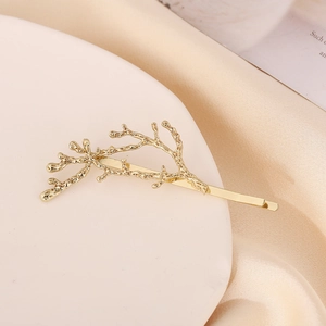 Gros plan d'une pince à cheveux dorée en forme de branche sur tissu en soie