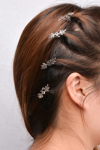 Detail view of four silver leaf-shaped hair clips styled on a female model side hair