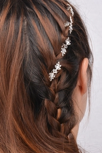 Detail shot of silver leaf hair clips set into a dark brown braided hairstyle