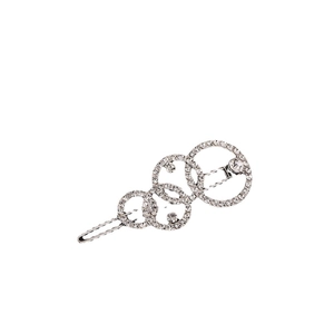 Détail d'une barrette argentée à anneaux entrelacés avec strass pavés et fermoir métallique