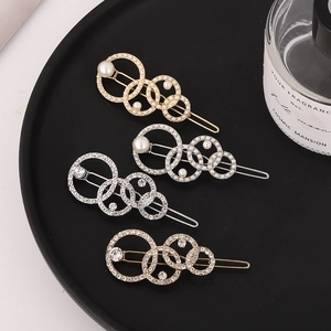 Barrettes élégantes en or et argent avec perles et strass sur un plateau mat