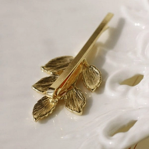 Barrette à cheveux vintage en feuille d'olivier dorée sur plateau en céramique élégant