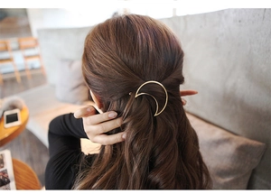 Close-up of a minimalist golden crescent moon hair clip worn on long wavy brown hair