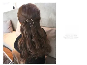 Minimalist golden crescent moon hair clip shown on brown curly ponytail hair