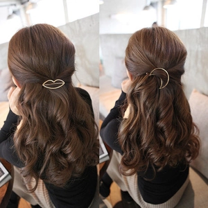 Geometric gold hollow crescent and lip hair clips worn on wavy hair in a cozy cafe