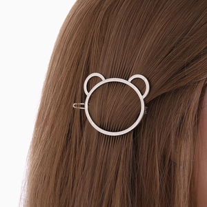 Minimalist silver hollow bear hair clip elegantly styled on long straight brown hair