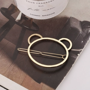 Minimalist gold metal hair clip with a hollow bear head design on a magazine