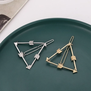 Pinces à cheveux flèche dorées et argentées en forme de triangle sur plateau vert