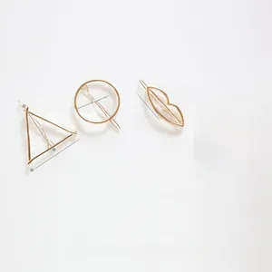 Detail view of a 4-piece set of gold geometric metal hair clips on a white background