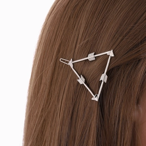 Pince à cheveux triangle géométrique argentée avec flèches sur cheveux bruns lisses