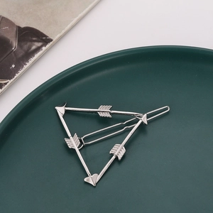 Barrette à cheveux triangle flèche argentée sur un plateau décoratif vert foncé