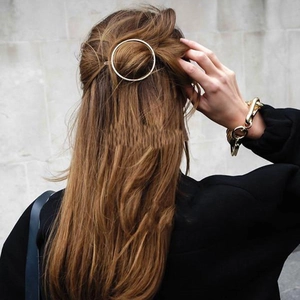 Minimalist circular gold-plated hair clip worn on long brown hair with metal bracelet