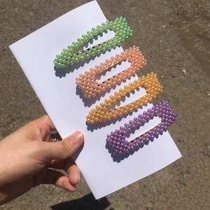 Primo piano di quattro fermagli per capelli con perle colorate in verde, rosa e viola