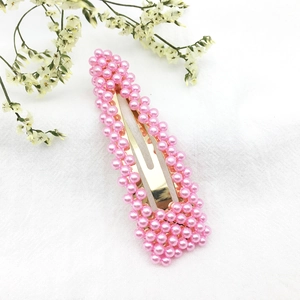 Dettaglio di perle rosa su un fermaglio dorato a goccia dal design dolce e chic