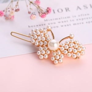 Eleganter goldener Schmetterlings-Haarclip mit weißen Perlen auf rosa Grund