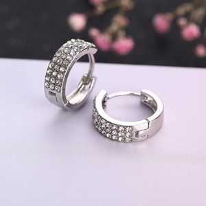 Détail de boucles d'oreilles créoles argentées serties de trois rangées de zircons