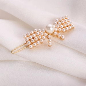 Eleganter goldener Schmetterling-Haarclip mit weißen Perlen auf weißem Samt