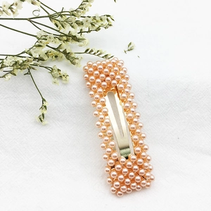 Dettaglio macro di perle rosa su un fermaglio per capelli dorato con finitura elegante