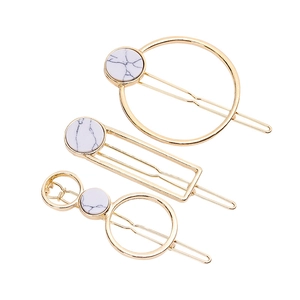 Three-piece geometric hair clip set in gold finish with white marble patterned accents