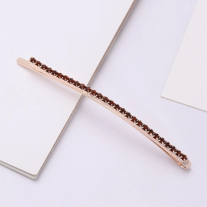 Elegant rose gold hair clip with deep red rhinestones on a minimalist background