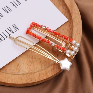 Detailed macro view of golden pearl hairpins and red bead star clips on a wooden tray