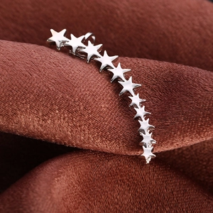 Detailed macro view of silver star ear crawler earrings on dark velvet background