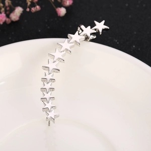 Detailed view of silver star ear cuff with eleven polished pentagrams on a white plate