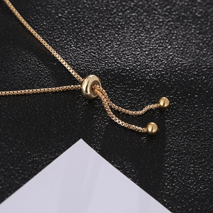 Detail of golden box chain bracelet featuring a polished adjustable sliding bead closure